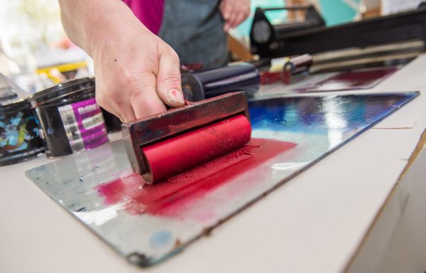 person rolling ink for printmaking